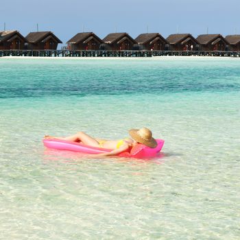 Woman relaxing on inflatable mattress at the beach