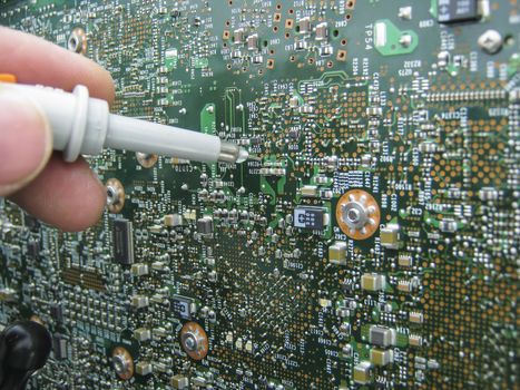 Multimeter probes examining a PCB circuit board