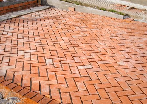 Orange brick paving stones pattern in the construction process of a courtyard