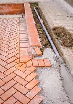 Orange brick paving stones pattern in the construction process of a courtyard