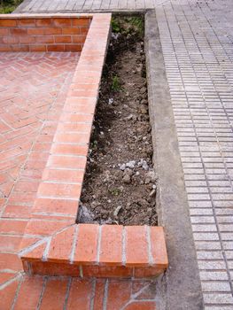 Low wall of outdoors courtyard built with orange brick paving stones