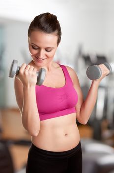 Woman working out with dumbbells at a gym, isolated in a gym
