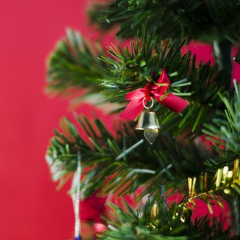 close up small bell on christmas tree on red background