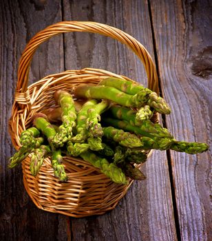 Asparagus Sprouts in Wicker Basket isolated on Rustic Wooden background