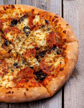 Pepperoni Pizza with Black Olives, Cheese and Spices Cross Section on Rustic Wooden background