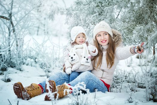 Attractive young mother holds daughter on hands and shows the side