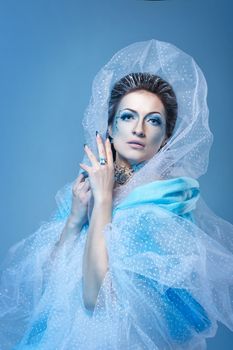 Attractive young girl with a theatrical makeup on the face in the image fabulous snow queen