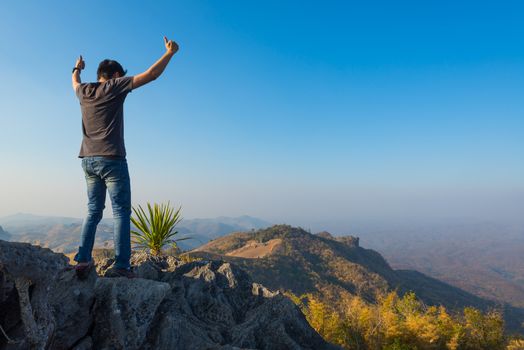 man standing on stone top of high mountain