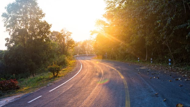 road in the mountain with yellow line and sunrise flare effect