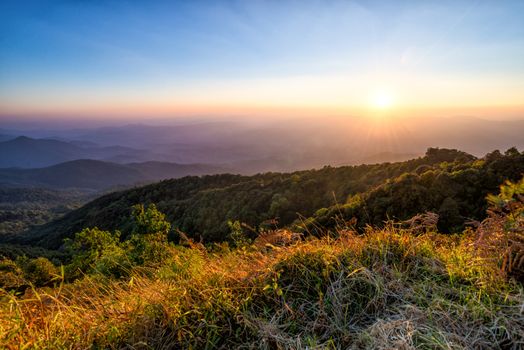 landscape of high mountain with sunset at horizon of sky and lens flare effect