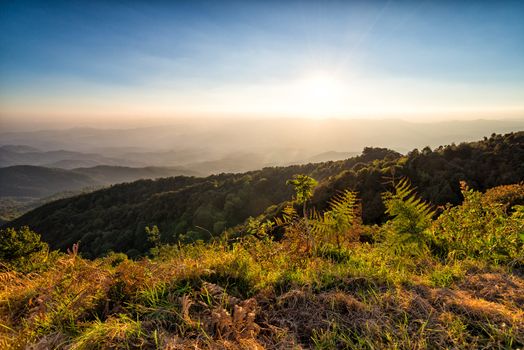 landscape of high mountain with sunset at horizon of sky and lens flare effect