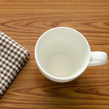 empty coffee cup on brown kitchen towel and wood table