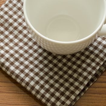 empty coffee cup on brown kitchen towel and wood table