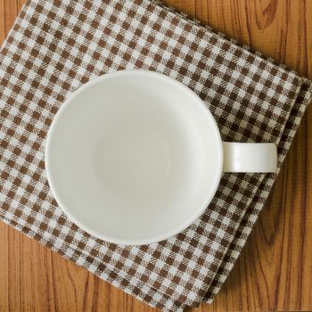 empty coffee cup on brown kitchen towel and wood table
