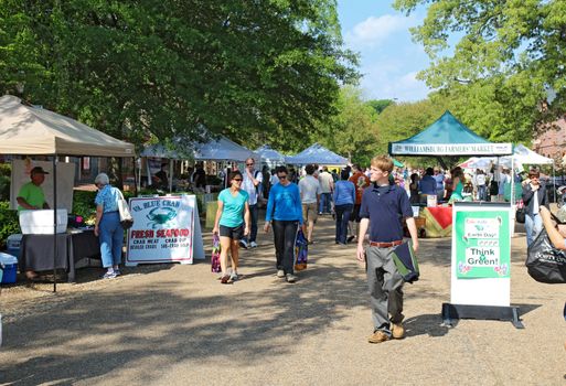 WILLIAMSBURG, VIRGINIA - APRIL 21 2012: Vendors and shoppers at the Williamsburg Farmers Market in spring. The restored town is a major attraction for tourists and meetings of world leaders.