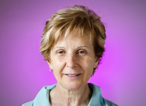 Portrait of a real happy middle aged woman over purple background