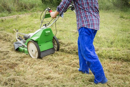 Young man mowing the lawn with a lawnmower machine