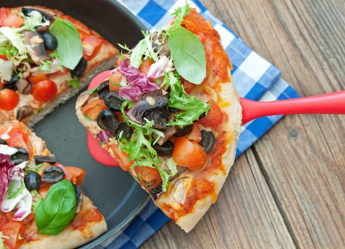 Deep pan pizza slice with tomatoes and mushrooms
