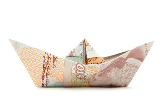Paper boat made from British pound banknotes over a white background 