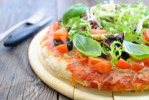 Close up of a deep pan pizza with basil, tomatoes and mushrooms