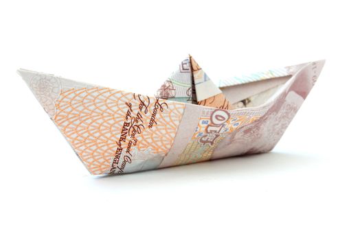 Paper boat made from British pound banknotes over a white background 