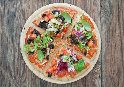 Stone baked pizza cut into slices on a chopping board 