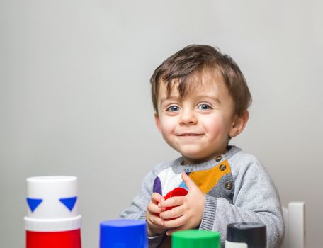 Child staring at the camera smiling while playing with toys