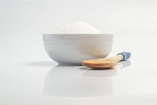 Bowl filled with sugar in white reflective surface