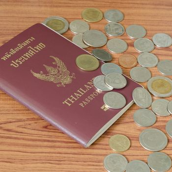 thai passport with coin on wood table background