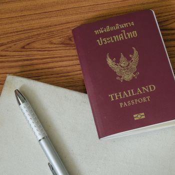 thai passport with notebook on wood table background