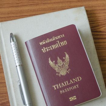 thai passport with notebook on wood table background