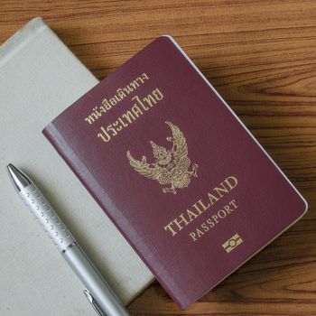 thai passport with notebook on wood table background