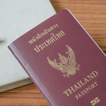 thai passport with notebook on wood table background