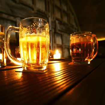Mugs of beer in dark bar close-up