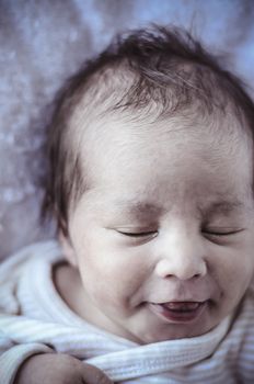 new born baby curled up sleeping on a blanket, multiple expressions