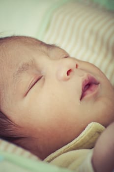 Newborn peacefully sleeping, picture of a baby curled up sleeping on a blanket