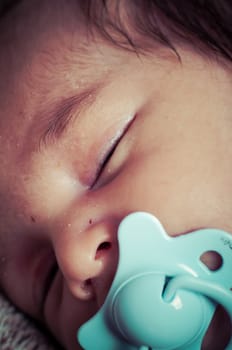 Newborn peacefully sleeping, picture of a baby curled up sleeping on a blanket