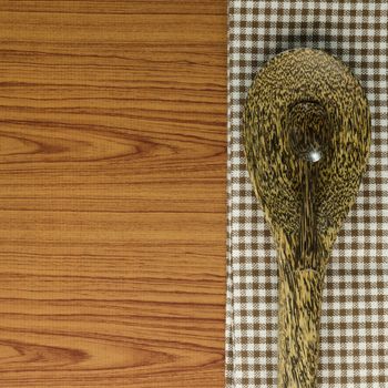 brown kitchen towel with spoon on wood background