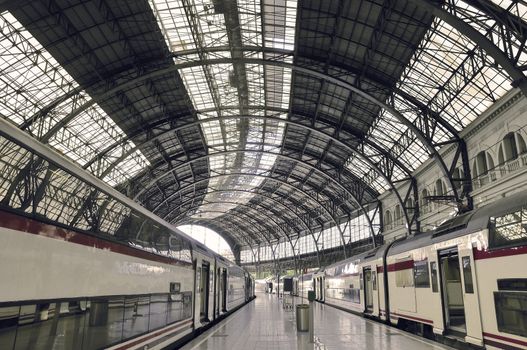 modern train station with waiting railroad cars and arc metallic roof
