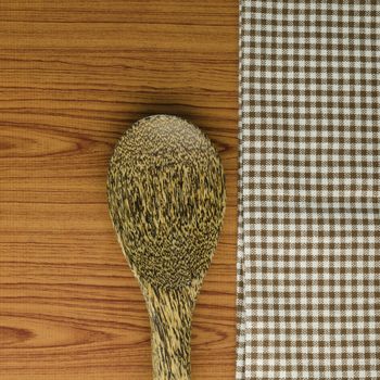 brown kitchen towel with spoon on wood background