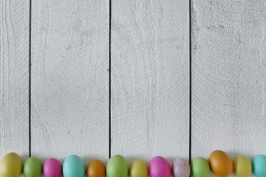 Spring or Easter Themed Background of Old Wood and Colored Eggs Lined Up