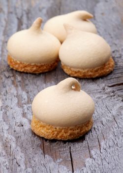 Arrangement of Swirled Meringue Topping with Biscuit Bottom isolated on Rustic Wooden background