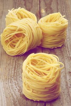 Four Nests of Raw Vermicelli isolated on Rustic Wooden background. Retro Styled.