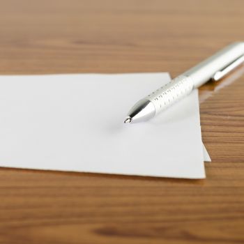 pen with white paper on wooden background