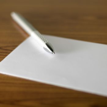 pen with white paper on wooden background