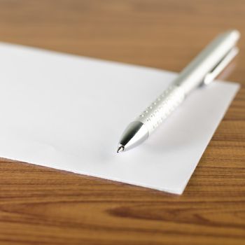 pen with white paper on wooden background