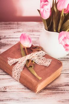 Memo still life with book, key, vintage lace and pink tulips