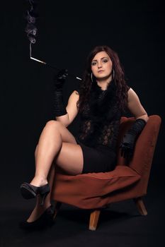 Young woman in retro clothes with cigarette sitting on old orange chair