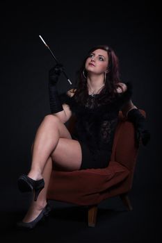 Young woman in retro clothes with cigarette sitting on old orange chair