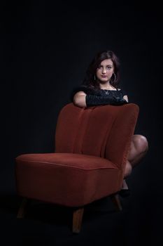 Young woman in retro clothes sitting on old orange chair